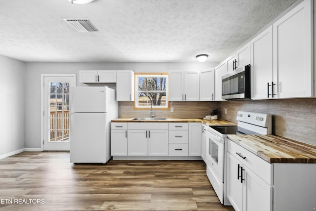 kitchen with hardwood / wood-style flooring, butcher block countertops, white cabinets, and white appliances