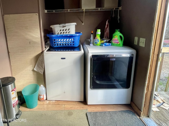 laundry area featuring washing machine and clothes dryer and light hardwood / wood-style flooring