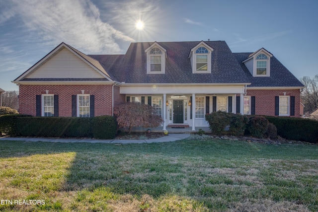 new england style home featuring covered porch and a front yard