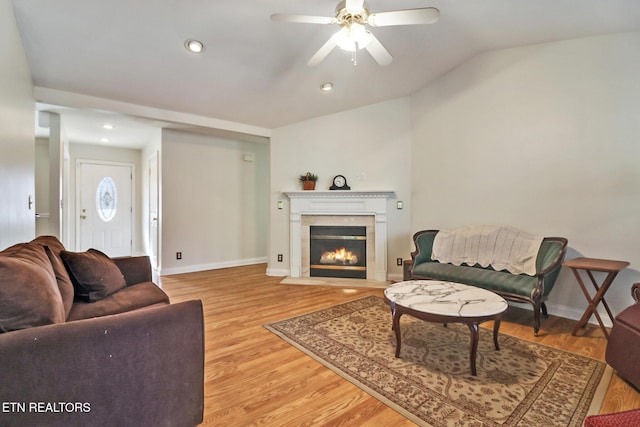 living room with ceiling fan, light hardwood / wood-style floors, and vaulted ceiling