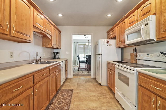 kitchen featuring an inviting chandelier, white appliances, and sink