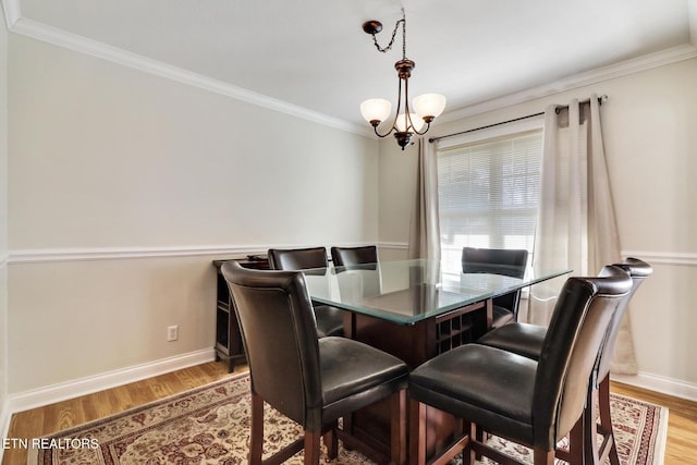 dining room with a notable chandelier, light hardwood / wood-style flooring, and ornamental molding