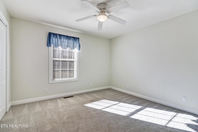 spare room with ceiling fan and carpet