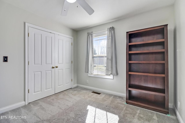 unfurnished bedroom featuring ceiling fan, light colored carpet, and a closet