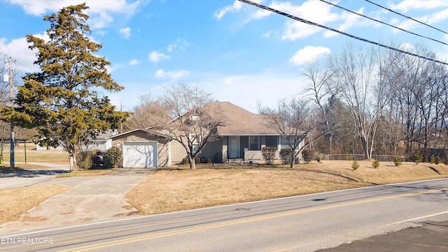 view of front of house with an attached garage, concrete driveway, a front yard, and fence