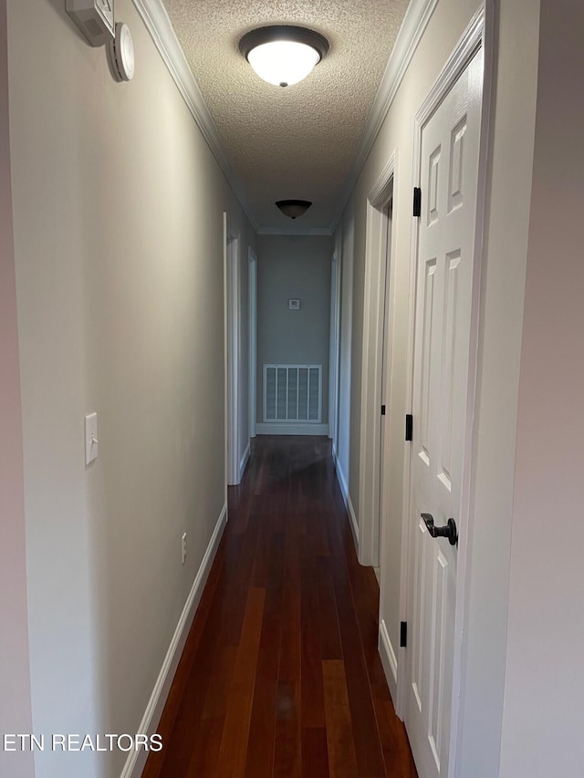 hallway featuring dark wood-type flooring, ornamental molding, and a textured ceiling