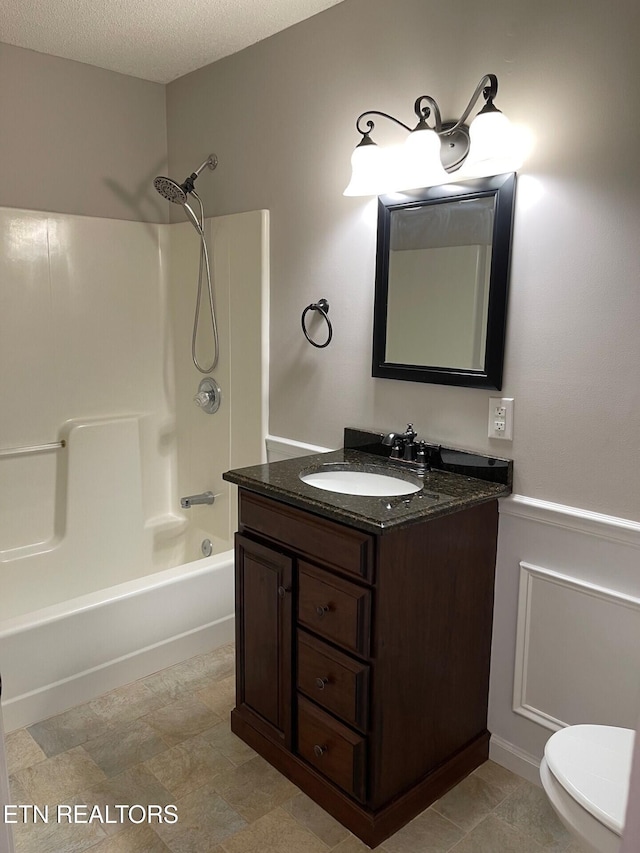 full bathroom featuring bathing tub / shower combination, vanity, a textured ceiling, and toilet