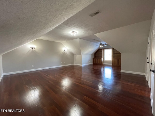 bonus room with dark wood-type flooring, lofted ceiling, and a textured ceiling