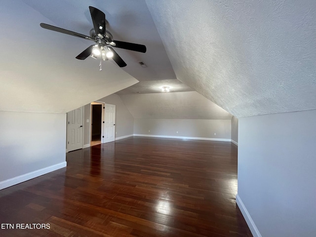 bonus room featuring vaulted ceiling, dark hardwood / wood-style floors, ceiling fan, and a textured ceiling