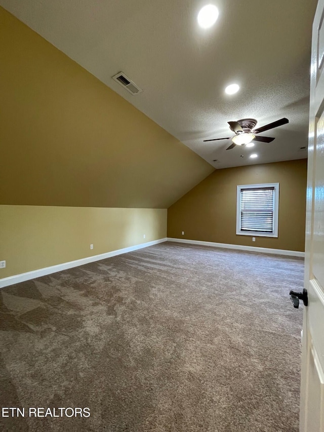 bonus room with vaulted ceiling, carpet floors, ceiling fan, and a textured ceiling