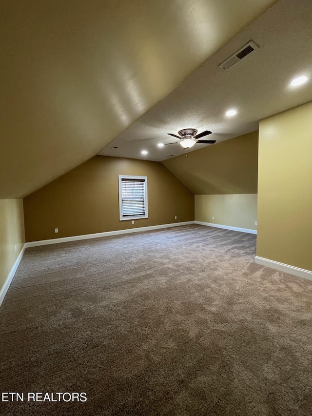 bonus room featuring lofted ceiling, carpet floors, a textured ceiling, and ceiling fan