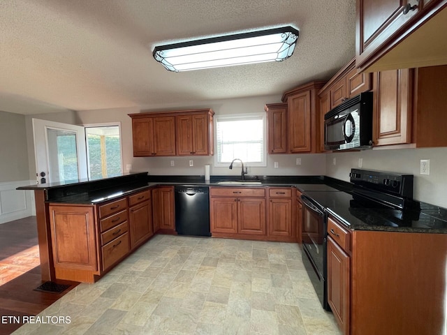 kitchen with black appliances, sink, dark stone counters, kitchen peninsula, and a textured ceiling