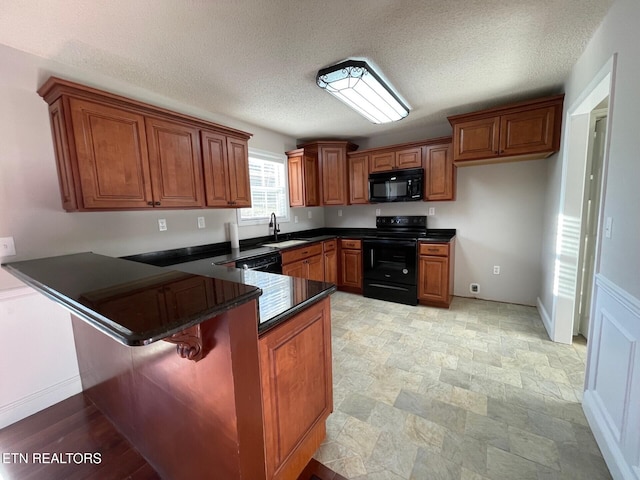 kitchen featuring a kitchen bar, sink, a textured ceiling, kitchen peninsula, and black appliances