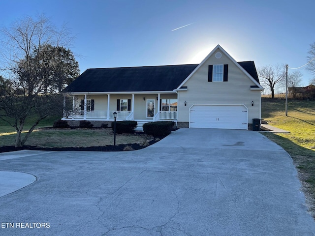 view of front of property featuring a garage, a front yard, and a porch