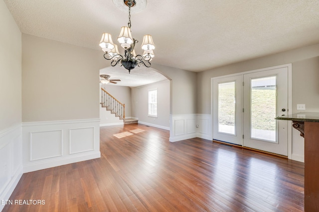 interior space with a wealth of natural light, a textured ceiling, a chandelier, and dark hardwood / wood-style floors