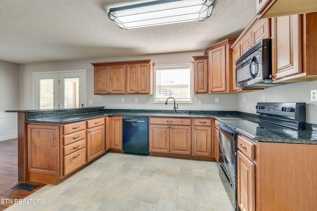kitchen featuring a textured ceiling, dark stone counters, black appliances, sink, and kitchen peninsula