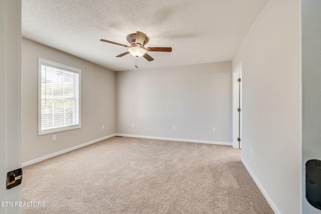 spare room featuring a textured ceiling, light colored carpet, and ceiling fan