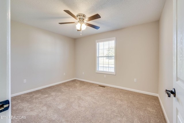 spare room with ceiling fan, a textured ceiling, and light colored carpet