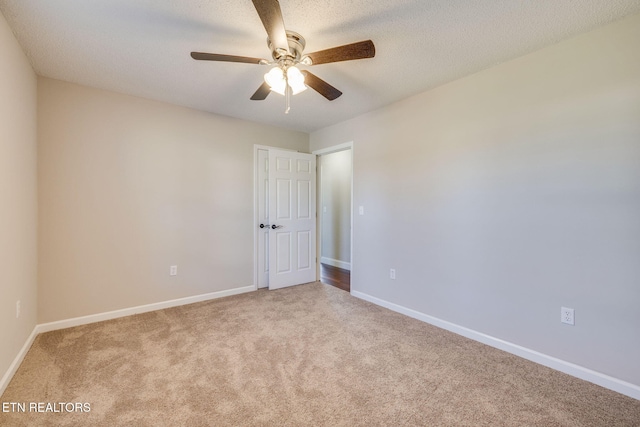 spare room featuring a textured ceiling, light colored carpet, and ceiling fan