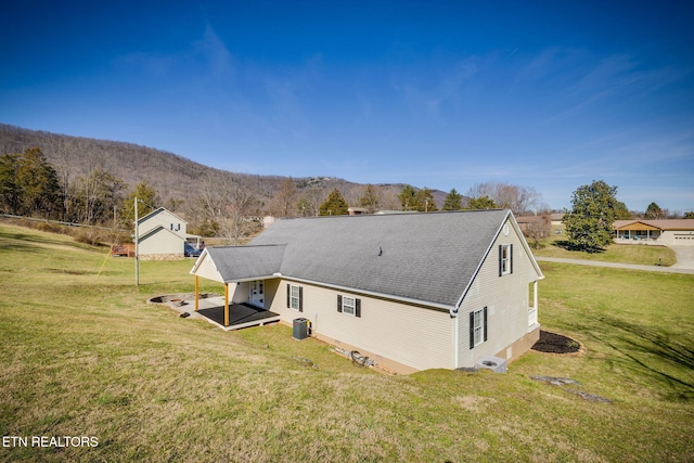 back of property with a lawn, a mountain view, and central AC unit
