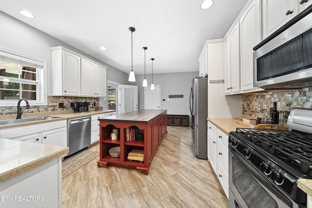 kitchen featuring white cabinetry, stainless steel appliances, decorative light fixtures, and sink