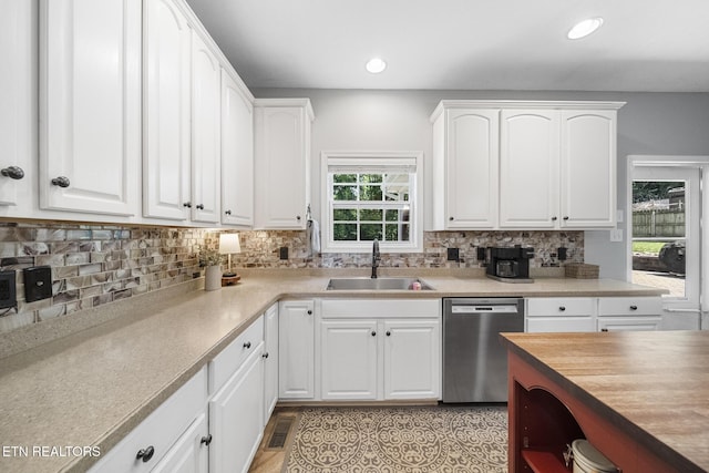 kitchen featuring tasteful backsplash, sink, stainless steel dishwasher, and white cabinets