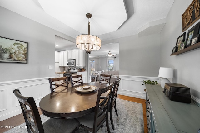 dining area featuring hardwood / wood-style flooring and ceiling fan with notable chandelier