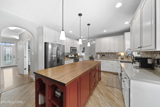 kitchen with stainless steel appliances, white cabinetry, a center island, and sink