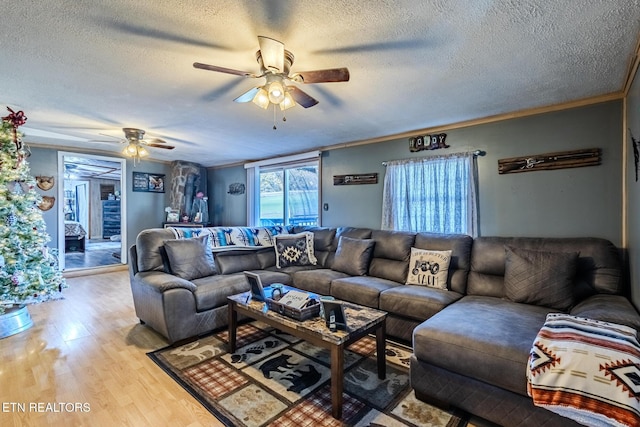 living room featuring crown molding, light hardwood / wood-style flooring, a textured ceiling, and ceiling fan