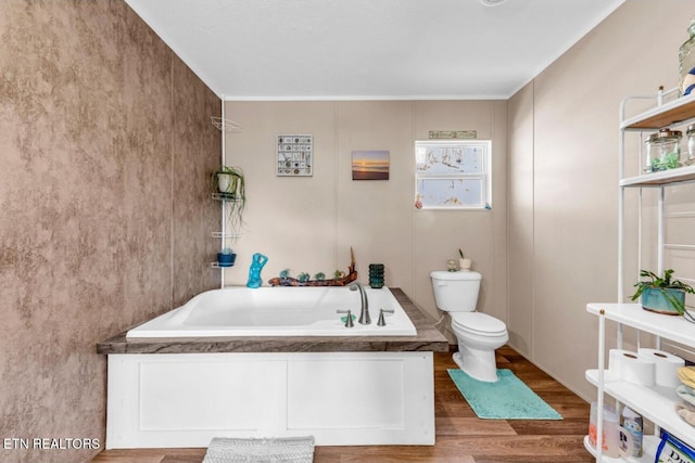 bathroom with hardwood / wood-style flooring, toilet, and a tub to relax in