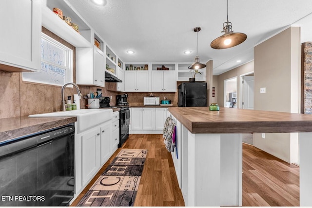 kitchen with white cabinetry, butcher block counters, hanging light fixtures, a center island, and black appliances