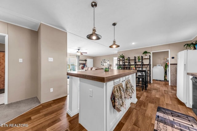 kitchen with hanging light fixtures, white refrigerator, white cabinets, wood counters, and washer / clothes dryer