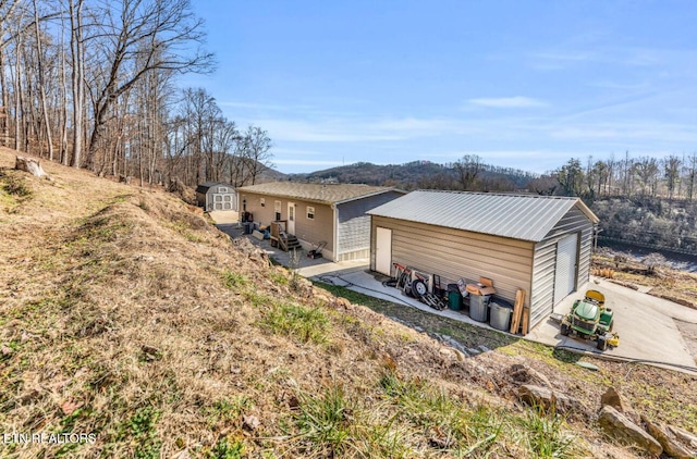 view of property exterior featuring a storage unit and a patio