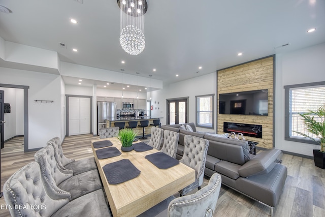 dining area with a stone fireplace, light hardwood / wood-style flooring, and a healthy amount of sunlight