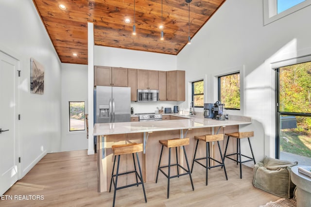 kitchen featuring wood ceiling, appliances with stainless steel finishes, kitchen peninsula, and a breakfast bar area