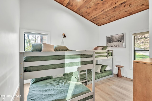 bedroom featuring multiple windows, lofted ceiling, light hardwood / wood-style floors, and wooden ceiling