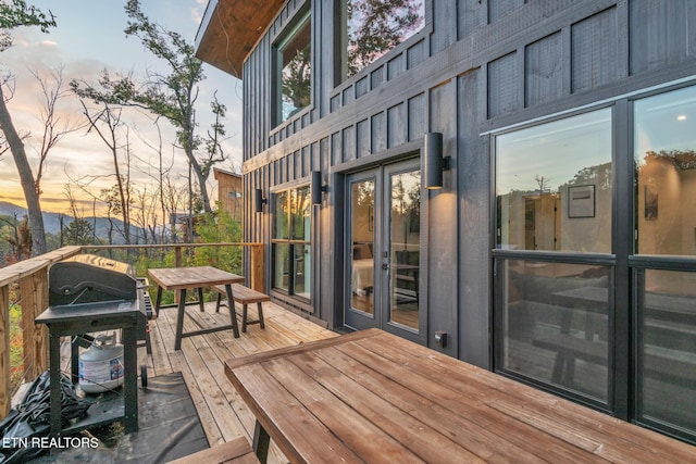 deck at dusk featuring a grill and french doors