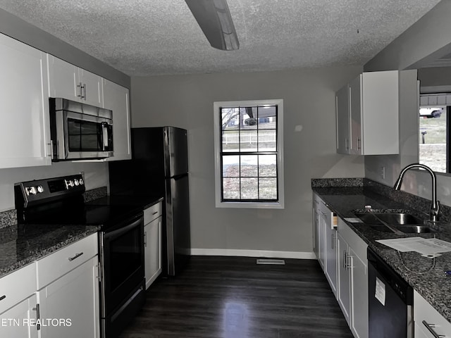 kitchen featuring white cabinetry, sink, dark hardwood / wood-style flooring, dark stone counters, and stainless steel appliances