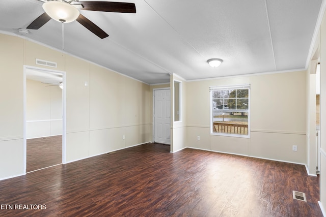 empty room with ceiling fan, vaulted ceiling, crown molding, and dark hardwood / wood-style flooring