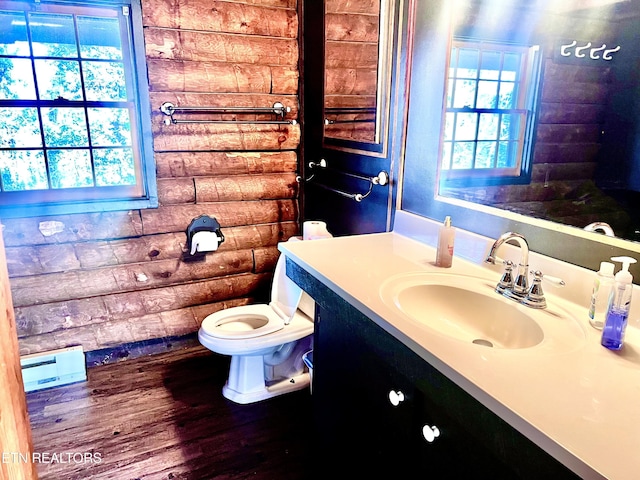 bathroom featuring hardwood / wood-style flooring, vanity, rustic walls, and toilet