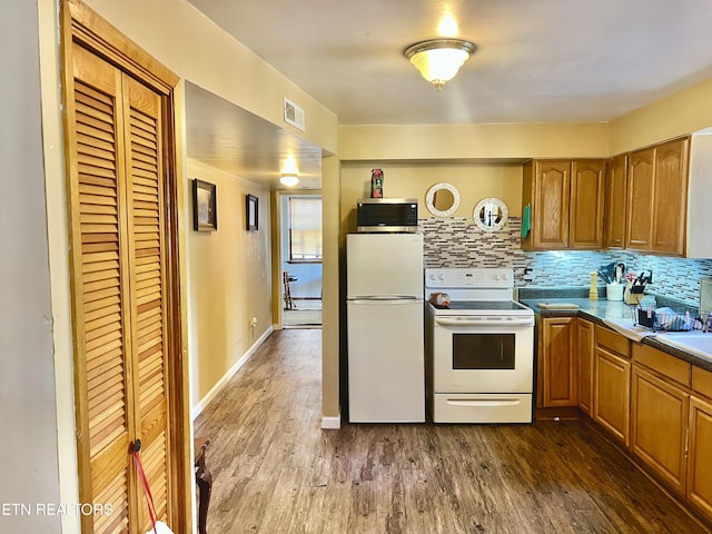 kitchen with white appliances, dark hardwood / wood-style floors, and decorative backsplash