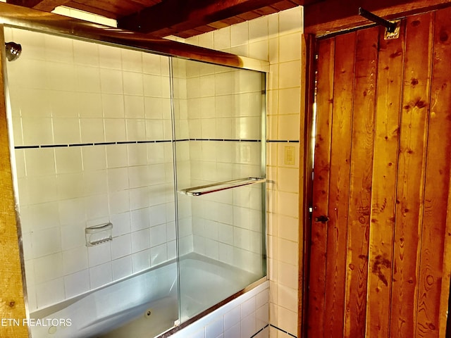 bathroom with beamed ceiling and combined bath / shower with glass door