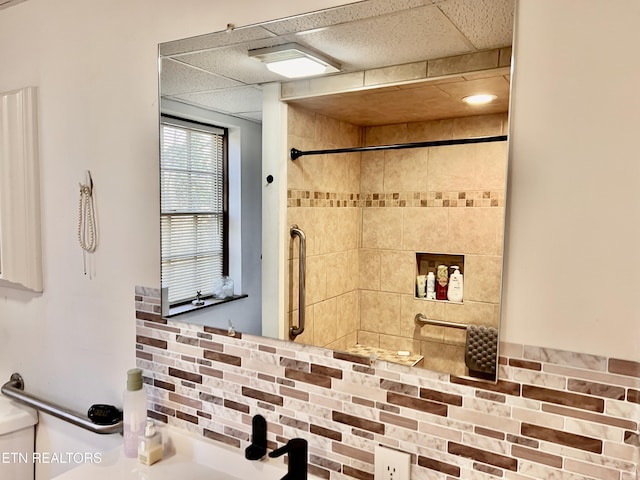 bathroom featuring a paneled ceiling, toilet, and tiled shower