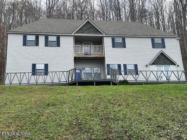 rear view of house featuring a yard and a balcony