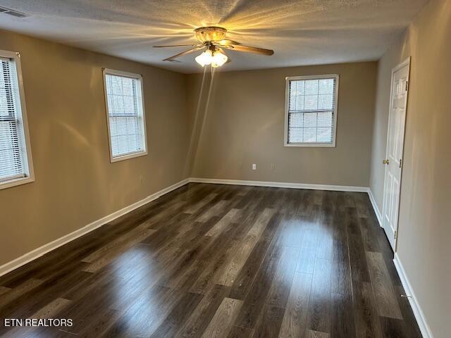 spare room with dark wood-type flooring and ceiling fan