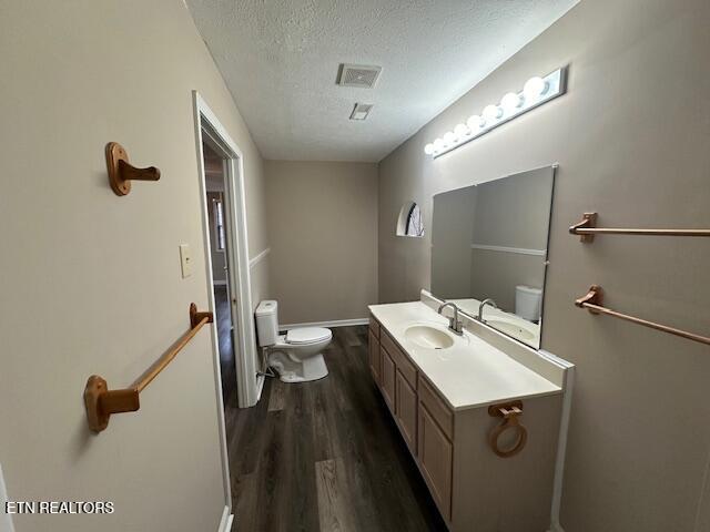 bathroom featuring hardwood / wood-style flooring, vanity, toilet, and a textured ceiling