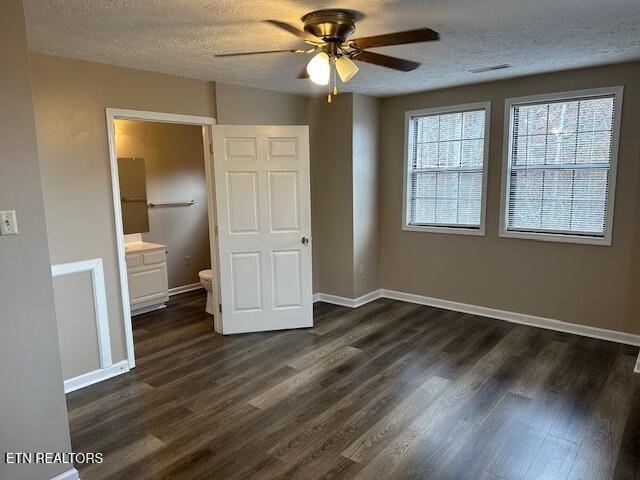 unfurnished bedroom with ceiling fan, dark hardwood / wood-style floors, a textured ceiling, and ensuite bathroom