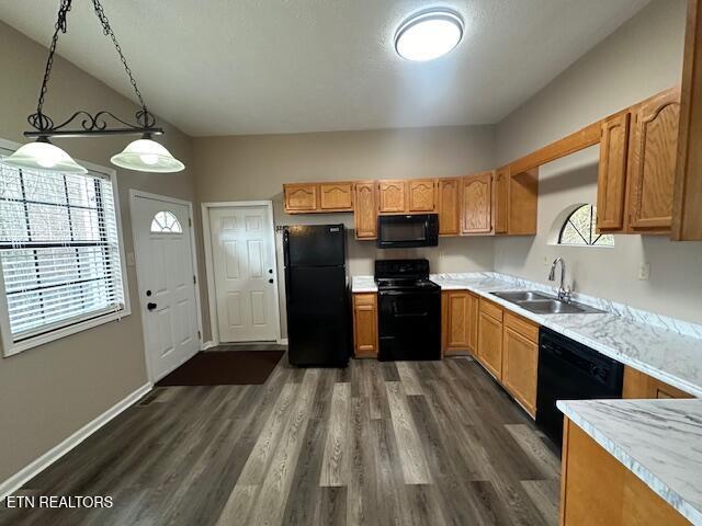 kitchen with sink, dark wood-type flooring, hanging light fixtures, black appliances, and vaulted ceiling