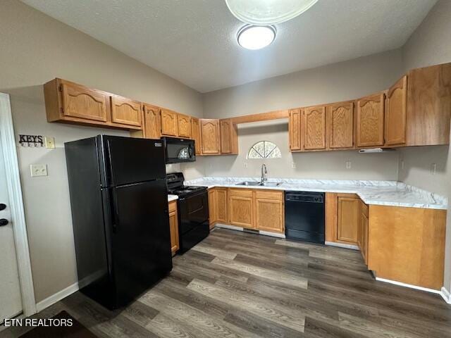 kitchen featuring sink, black appliances, a textured ceiling, dark hardwood / wood-style flooring, and vaulted ceiling