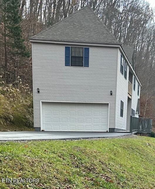 view of side of home featuring a garage and a lawn